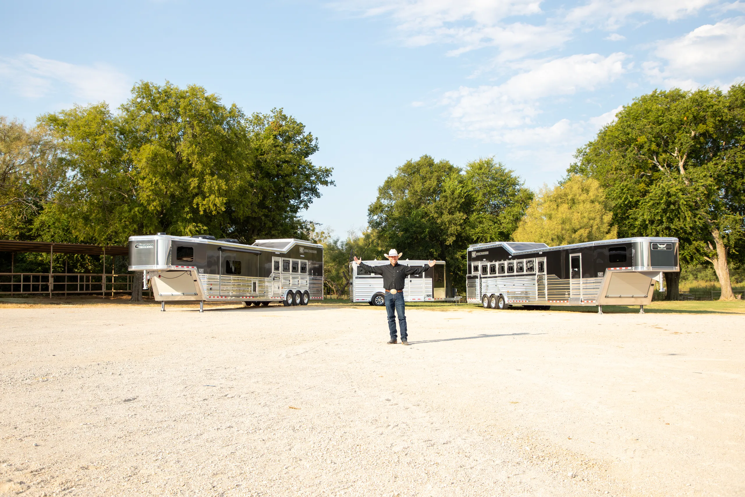 Trevor Brazile standing before multiple trailers, arms outstretched