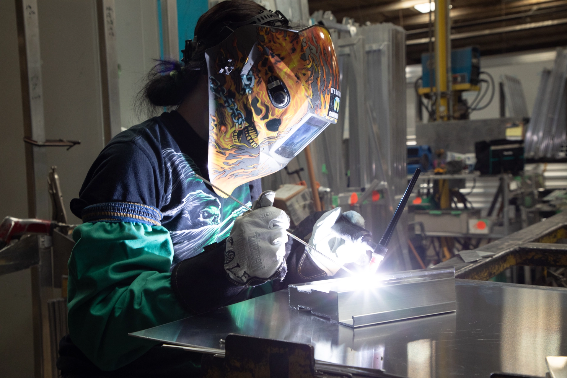 A person with a skull-decorated helmet welding